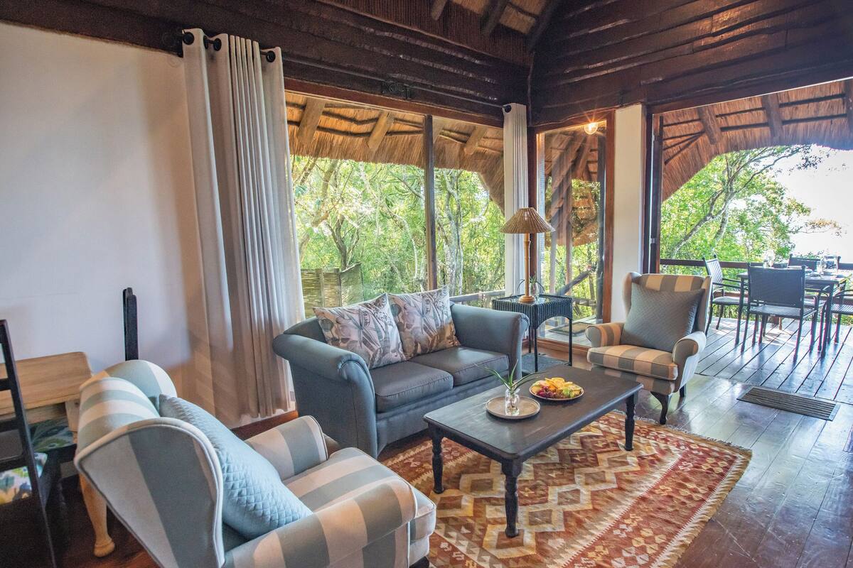 Uma sala de estar acolhedora, com um sofá, poltronas, uma mesa de centro e um tapete.