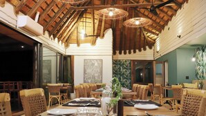 A restaurant with wooden ceiling beams, wicker chairs, and tables set for dining. - Sobhengu Lodge by Dream Resorts (KwaNibela)