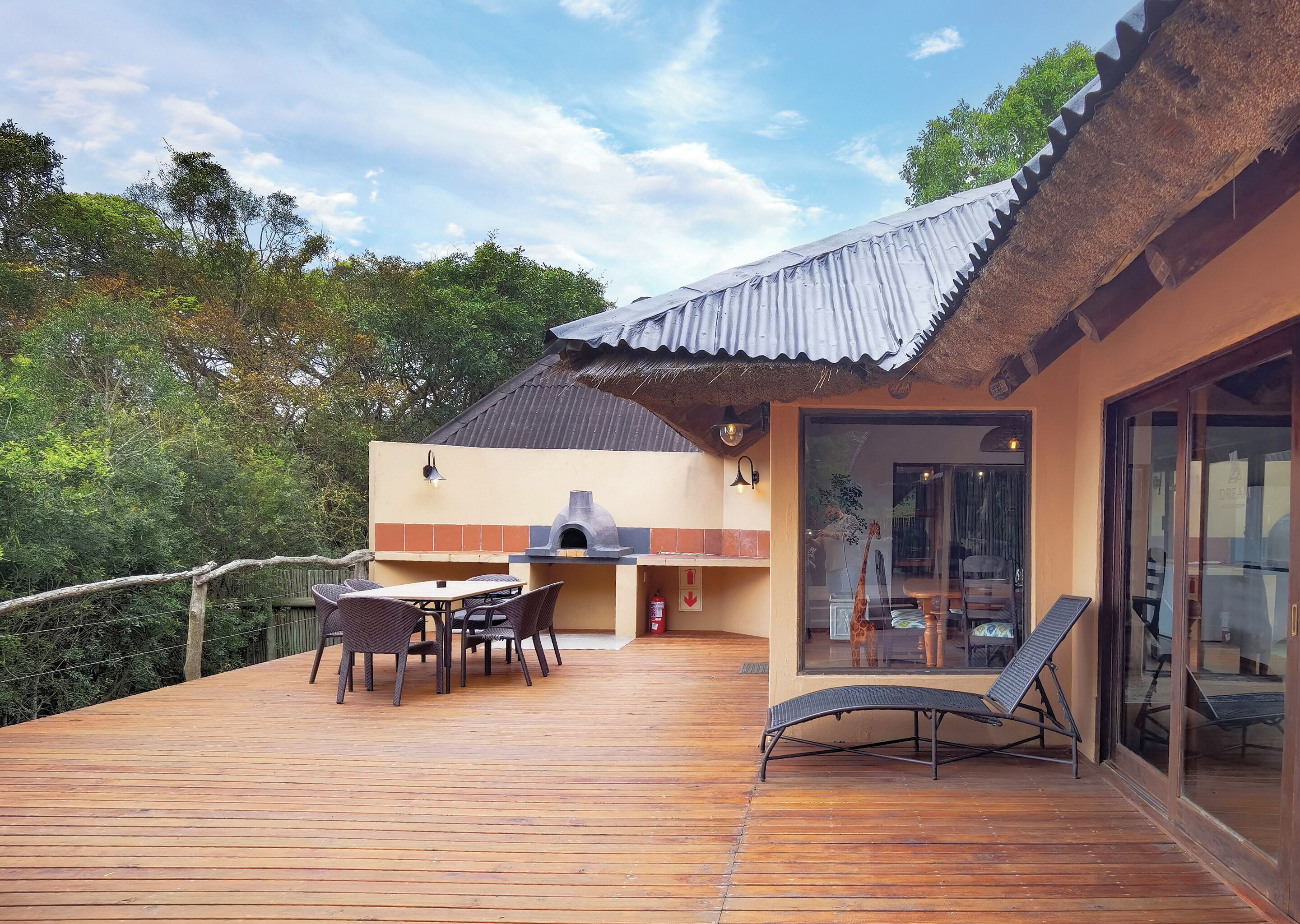 Una terraza de madera con comedor, una parrilla y una silla de descanso.