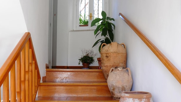 A staircase with terracotta tiles and wooden railings, leading to a room with a window and potted plants. - B&B La Cascata   Camera Positano (Amalfi)