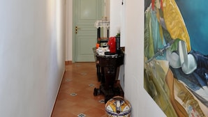 A hallway with a tiled floor, a green door, a table with a vase, and a large painting on the wall. - B&B La Cascata   Camera Positano (Amalfi)