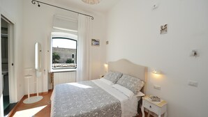 A bedroom with a bed, bedside table, and a window with curtains. - B&B La Cascata   Camera Positano (Amalfi)