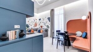 Un espacio habitable moderno con zona de cocina, una mesa de comedor y una sala de estar con un muro curvo naranja.