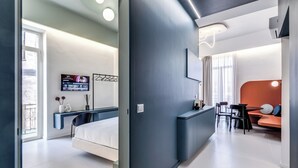 Una habitación de hotel moderna con cama, escritorio, televisión y zona de comedor con mesa y sillas.