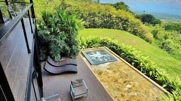 A terrace with outdoor furniture, a hot tub, and a view of a lush landscape.
