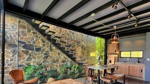 A spacious interior with a stone wall, a wooden bench, a cowhide rug, and a staircase. - Landscape Suite (Cerritos)