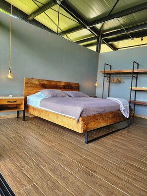 A wooden bed with a headboard, a nightstand, and a hanging light fixture.