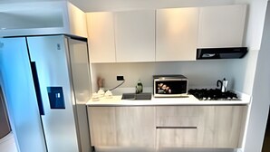 Et moderne køkken med hvide skabe, indbygget ovn og emhætte i rustfrit stål.