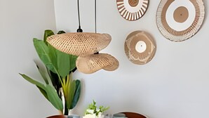 Et rundt spisebord med fire stole, en vase med hvide blomster, og et hængende lysarmatur.