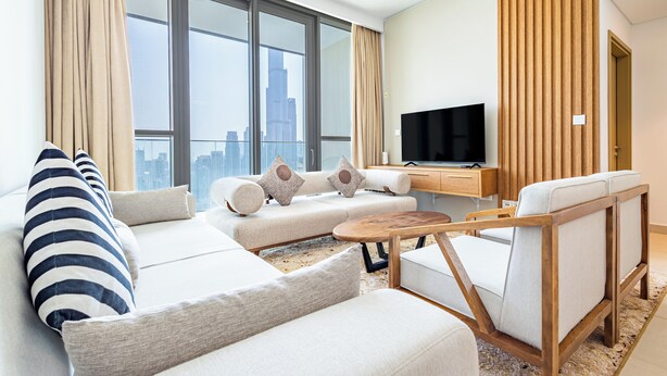 Ein modernes Wohnzimmer mit einer Sofagarnitur, einem Holztisch und einem Fernseher auf einem Holzgestell.