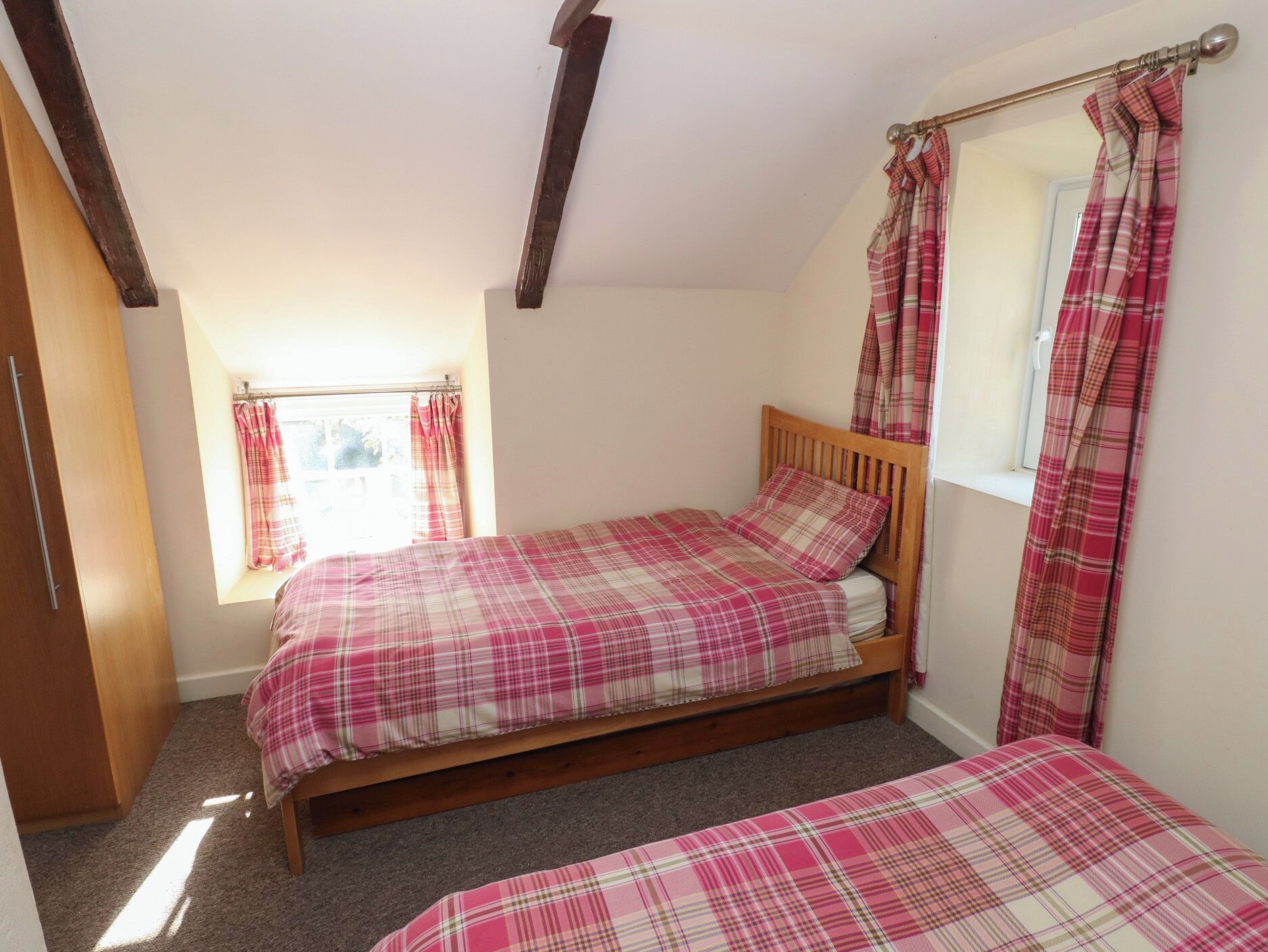 A bedroom with a wooden bed, a window with curtains, and a wardrobe.