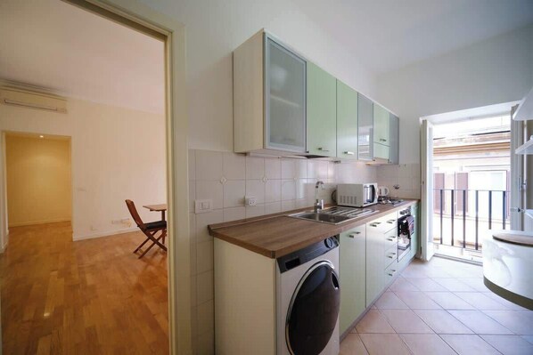 A compact kitchen with a washing machine, a microwave, and a small dining area.