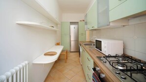 Una cucina compatta con piano cottura a gas, forno a microonde e frigorifero.