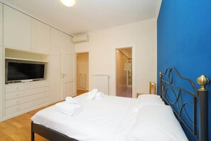 Un dormitorio con cama, televisor y armario.