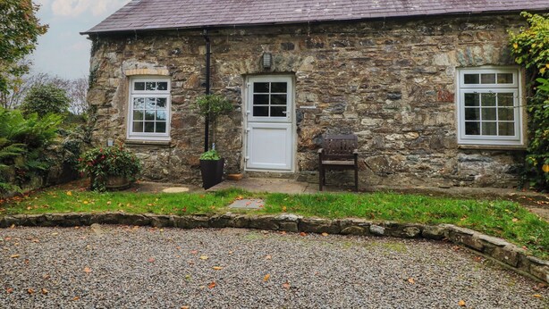 A stone building with a gravel driveway and a small garden area.