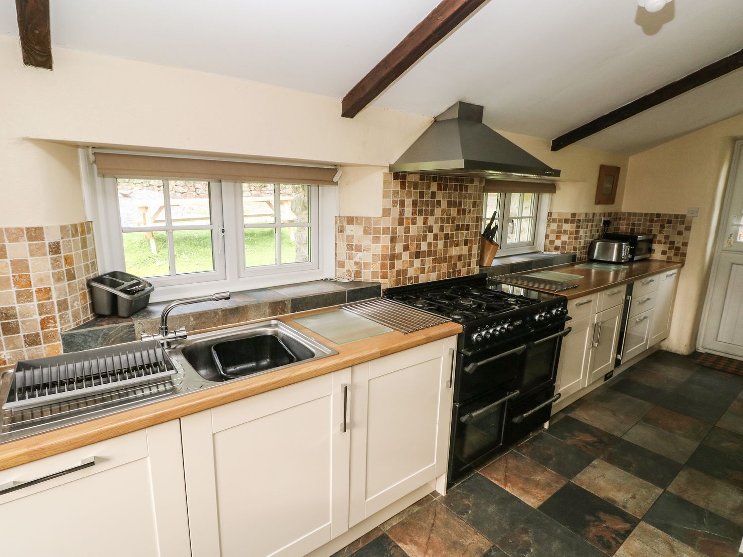 A kitchen with a stove, sink, and a window with a view of the outdoors.