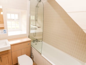 Et badeværelse med brusekabine i glas, toilet, håndvask og et vindue.