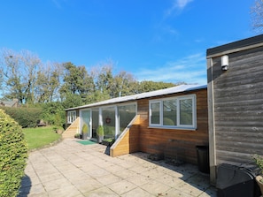 A wooden cabin with a covered patio, a small staircase, and a view of the surrounding trees. - Lake Cottage (Clarbeston Road)
