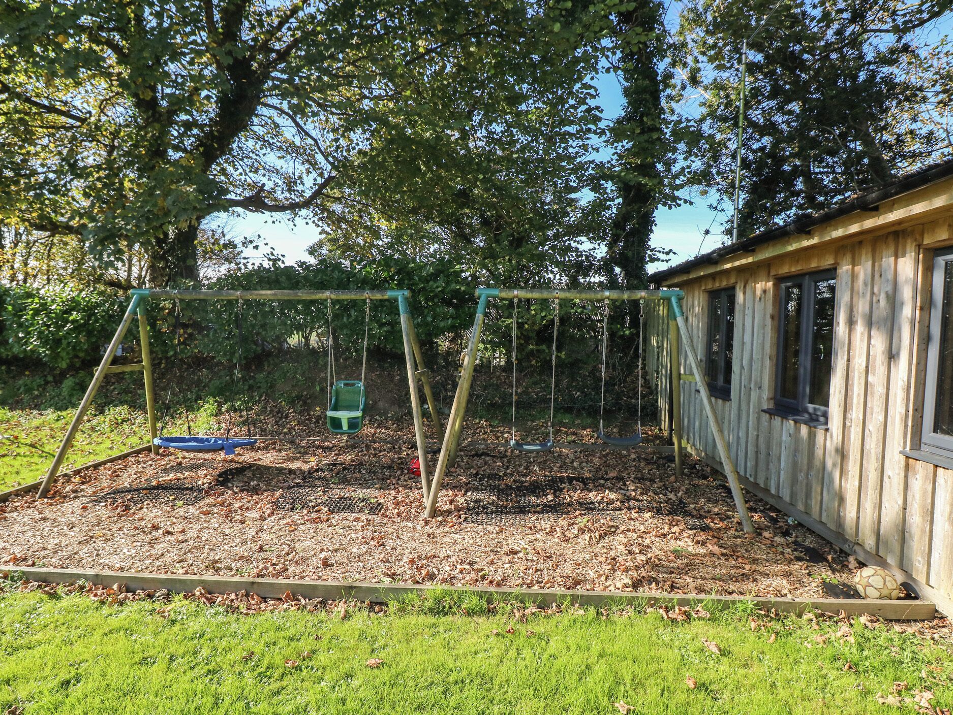Ein hölzernes Spielhaus mit Schaukel im Garten.