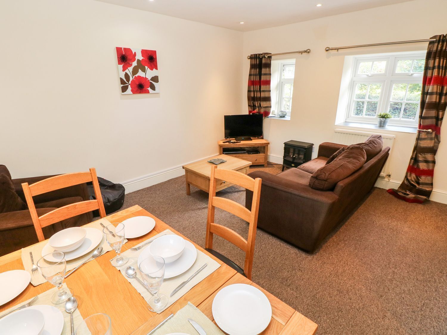A living room with a sofa, a TV, and a dining area with a table set for four.