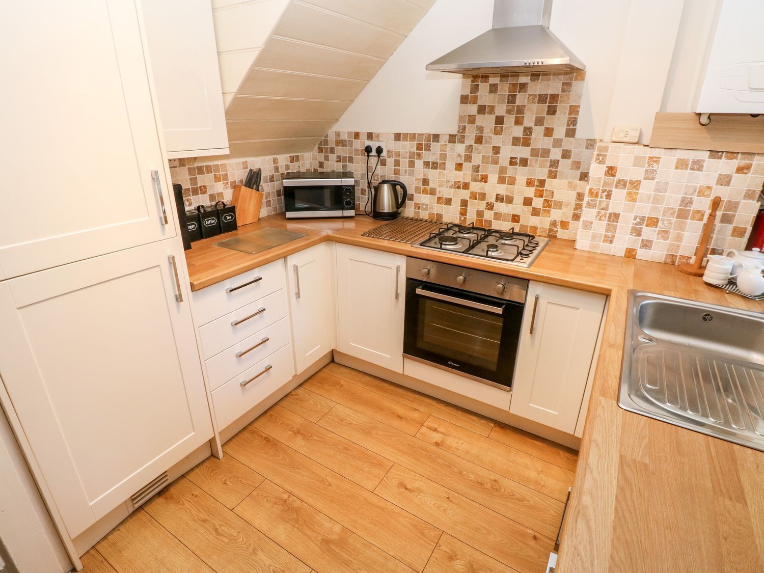 A compact kitchen with white cabinets, a microwave, a gas stove, and a built-in oven.