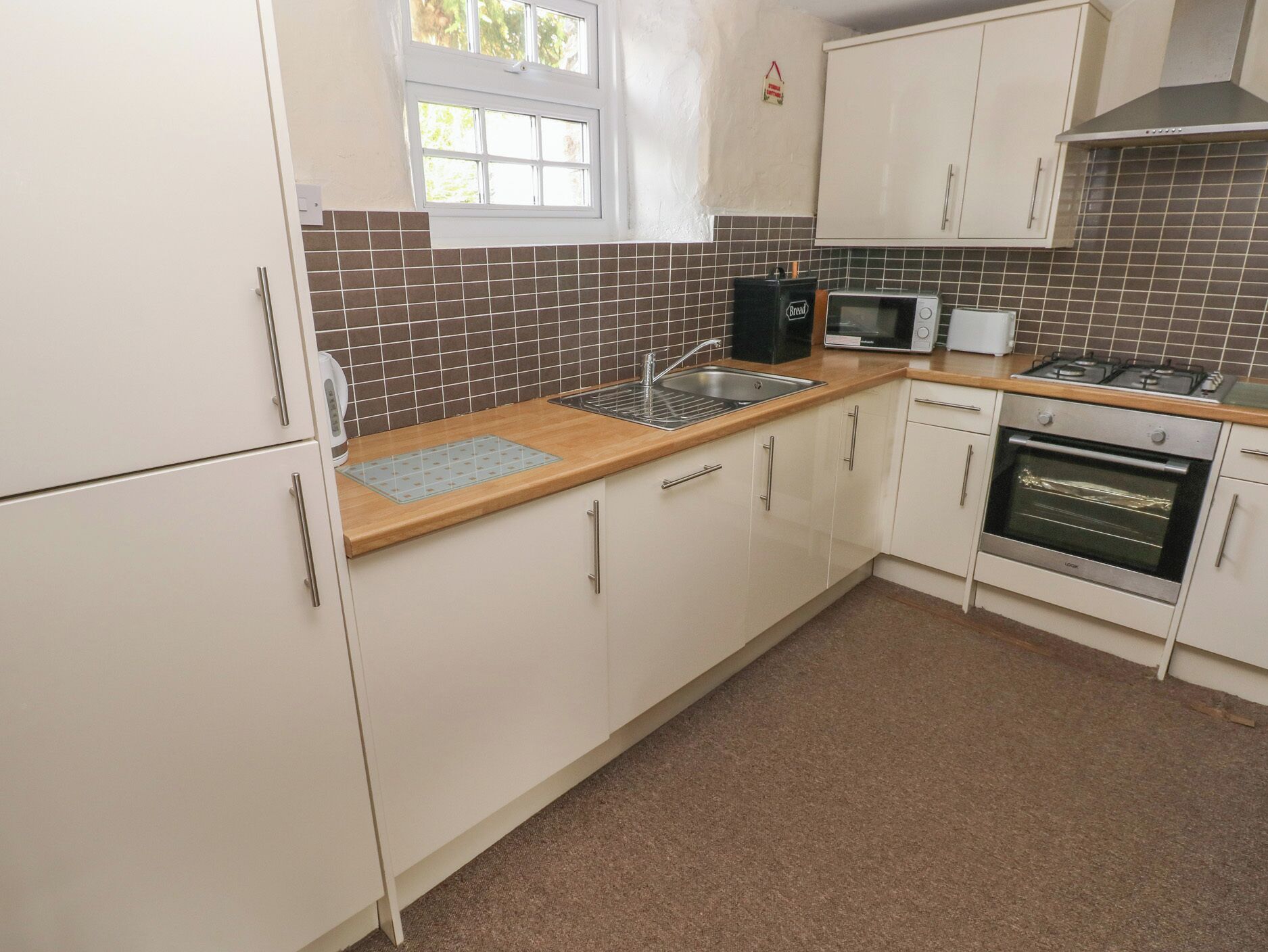 A kitchen with white cabinets, a microwave, a toaster, and a gas stove.