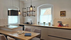 Et moderne køkken med en central ø, hængende lamper og et vindue med udsigt.