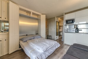 Una habitación compacta con cama, kitchenette y una pequeña zona de estar.