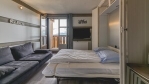 Een kamer met een bed, een bank, een televisie en uitzicht op het omliggende landschap.