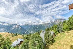 A mountainous landscape with a small building surrounded by trees.