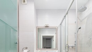 Une salle de bain moderne dotée d’une douche à parois de verre, d’un lave-linge encastré et de toilettes.