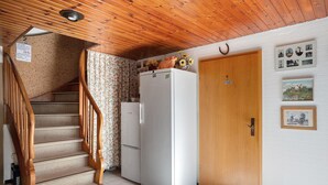 Una cocina con escalera de madera, un refrigerador blanco y una puerta de madera.