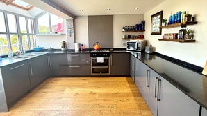 A modern kitchen with a large island, built-in oven, microwave, and a kettle. - Cornish cottage.  Sleeps 8.  Dog friendly.  Lake views.  Close to the coast. (Millbrook)