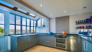 A modern kitchen with large windows, a gas stove, oven, and microwave. - Cornish cottage.  Sleeps 8.  Dog friendly.  Lake views.  Close to the coast. (Millbrook)