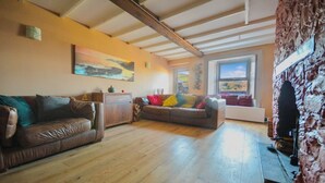 A living room with two sofas, a wooden cabinet, and a fireplace. - Cornish cottage.  Sleeps 8.  Dog friendly.  Lake views.  Close to the coast. (Millbrook)