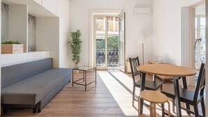 A modern living room with a grey sofa, a wooden dining table with chairs, a glass coffee table, and a potted plant. - Turati Apartment al Politeama by Wonderful Italy (Palermo)