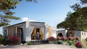 Une maison moderne à deux étages, dotée d’un porche couvert, d’un petit espace de détente extérieur et d’une allée gravillonnée.