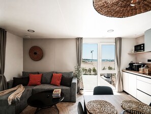 A modern living room with a sofa, coffee table, and a view of the beach through the glass door.