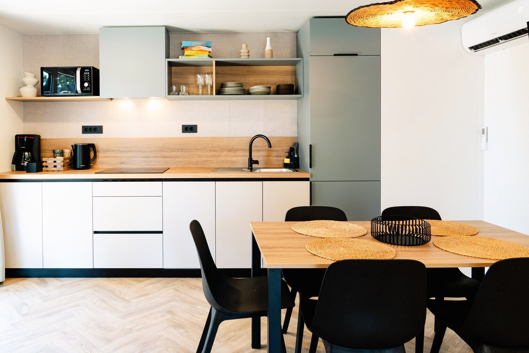 A modern kitchen with a microwave, coffee maker, and a dining area with a table and chairs.