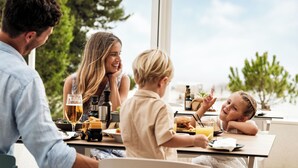 Une famille est assise à une table, profitant d’une vue sur les arbres et un ciel dégagé.