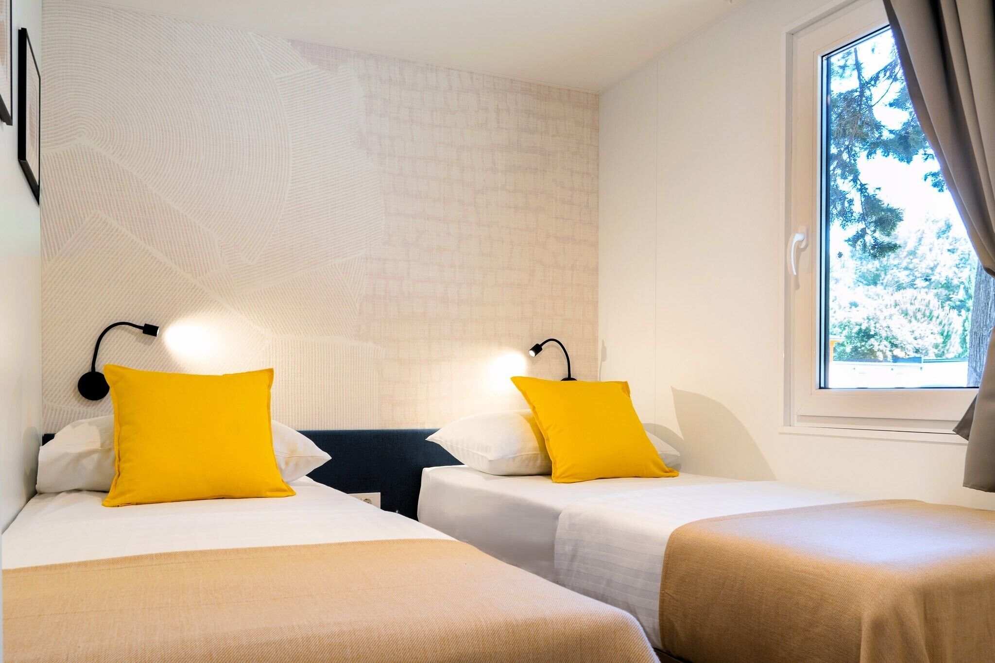 Une chambre d’hôtel avec deux lits, une fenêtre avec des rideaux et un mur à motifs.