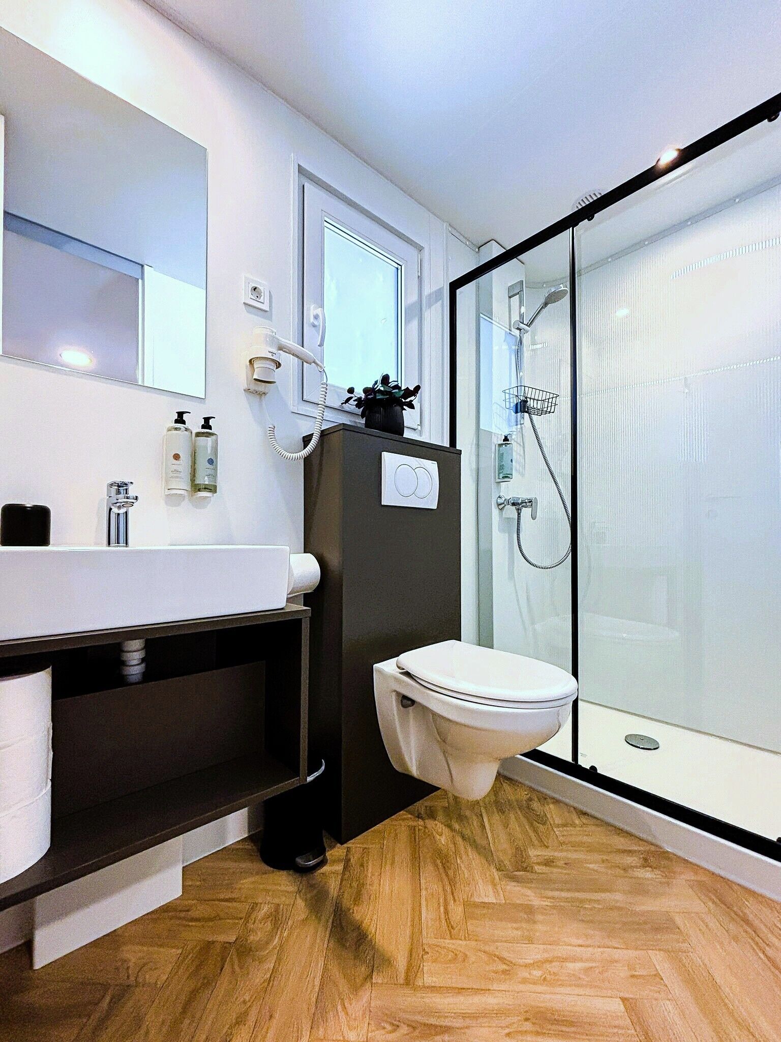 Un baño moderno con inodoro, lavamanos y ducha.