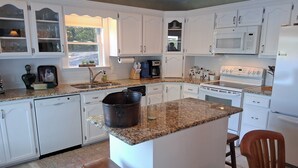 A kitchen with white cabinets, a granite countertop, a stove, a microwave, and a sink.