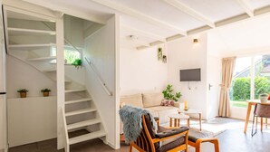 Ein modernes Wohnzimmer mit Treppe, Sofa, Couchtisch und Fernseher.