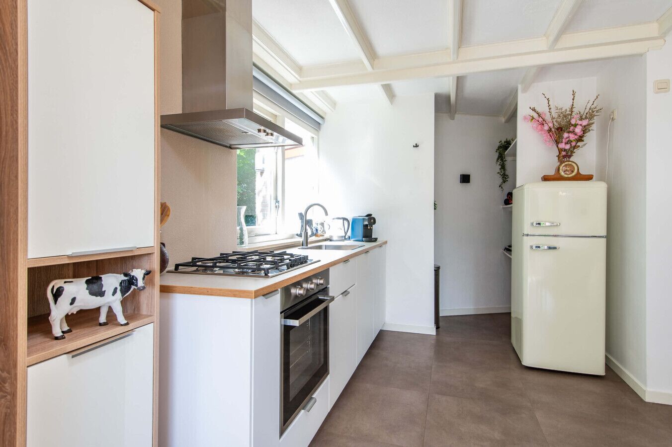 Una cocina moderna con estufa a gas, horno y un refrigerador antiguo.