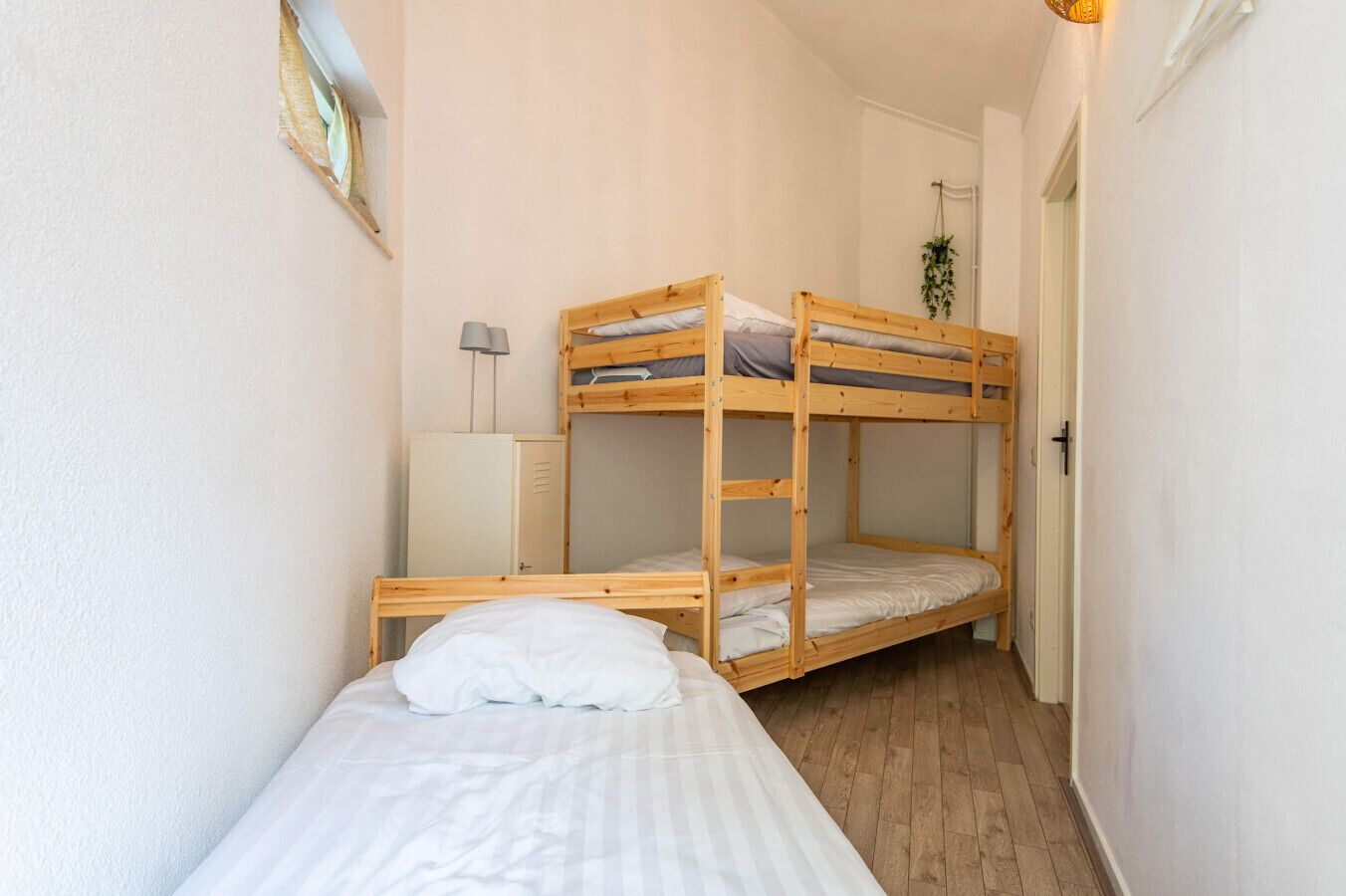 Une chambre de dortoir avec des lits superposés, un bureau et une lampe.