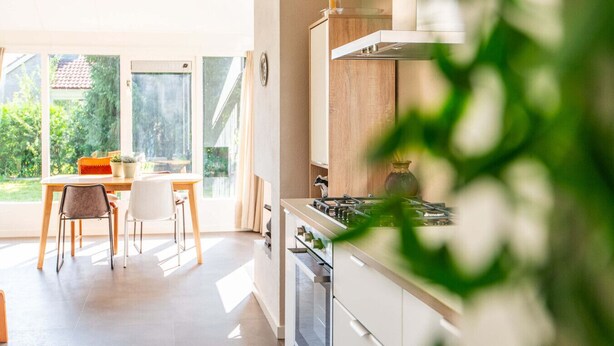Eine moderne Küche mit Gaskochfeld, Holzschränken und einem Essbereich mit Tisch und Stühlen.