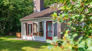 Ein gemütliches Haus mit Garten, einem Essbereich mit Tisch und Stühlen sowie einem Schornstein.