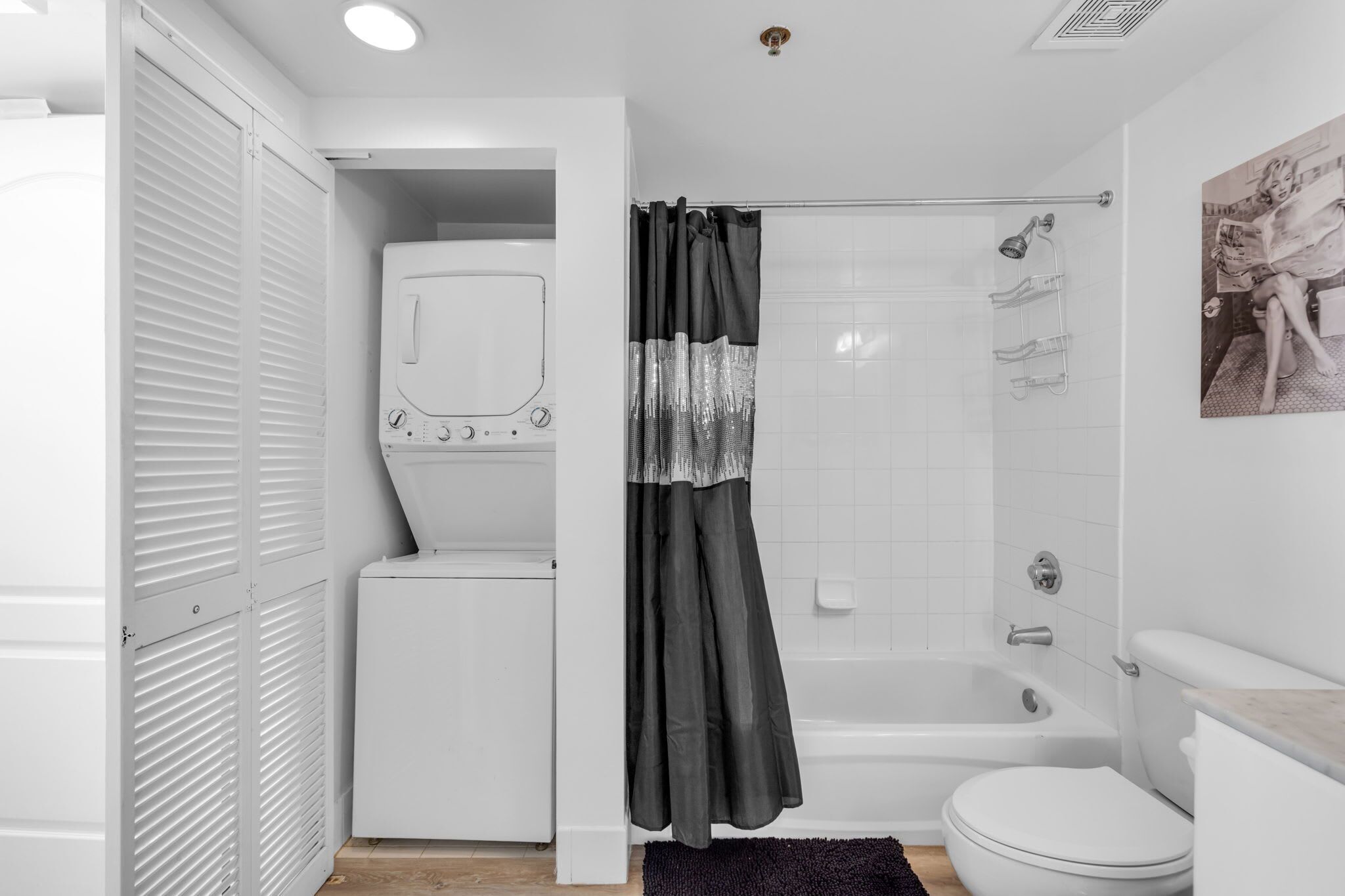 A compact bathroom with a built-in washer and dryer, a shower with a glass door, and a toilet.