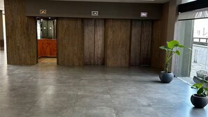A spacious lobby with a modern design, featuring a wooden reception desk, a glass elevator, and potted plants. - Entire condo in San Carlos de Bariloche, Argentina (San Carlos de Bariloche)